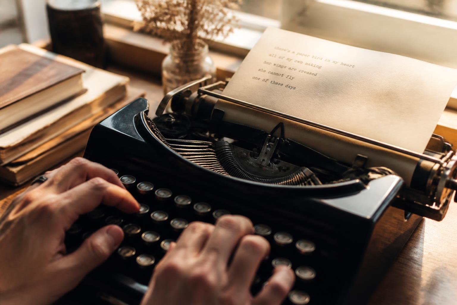 Hands typing on a vintage typewriter with a half-written page